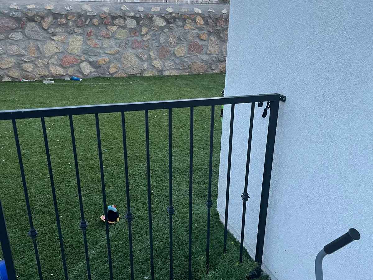 Fenced back yard with artificial turf and a rock wall