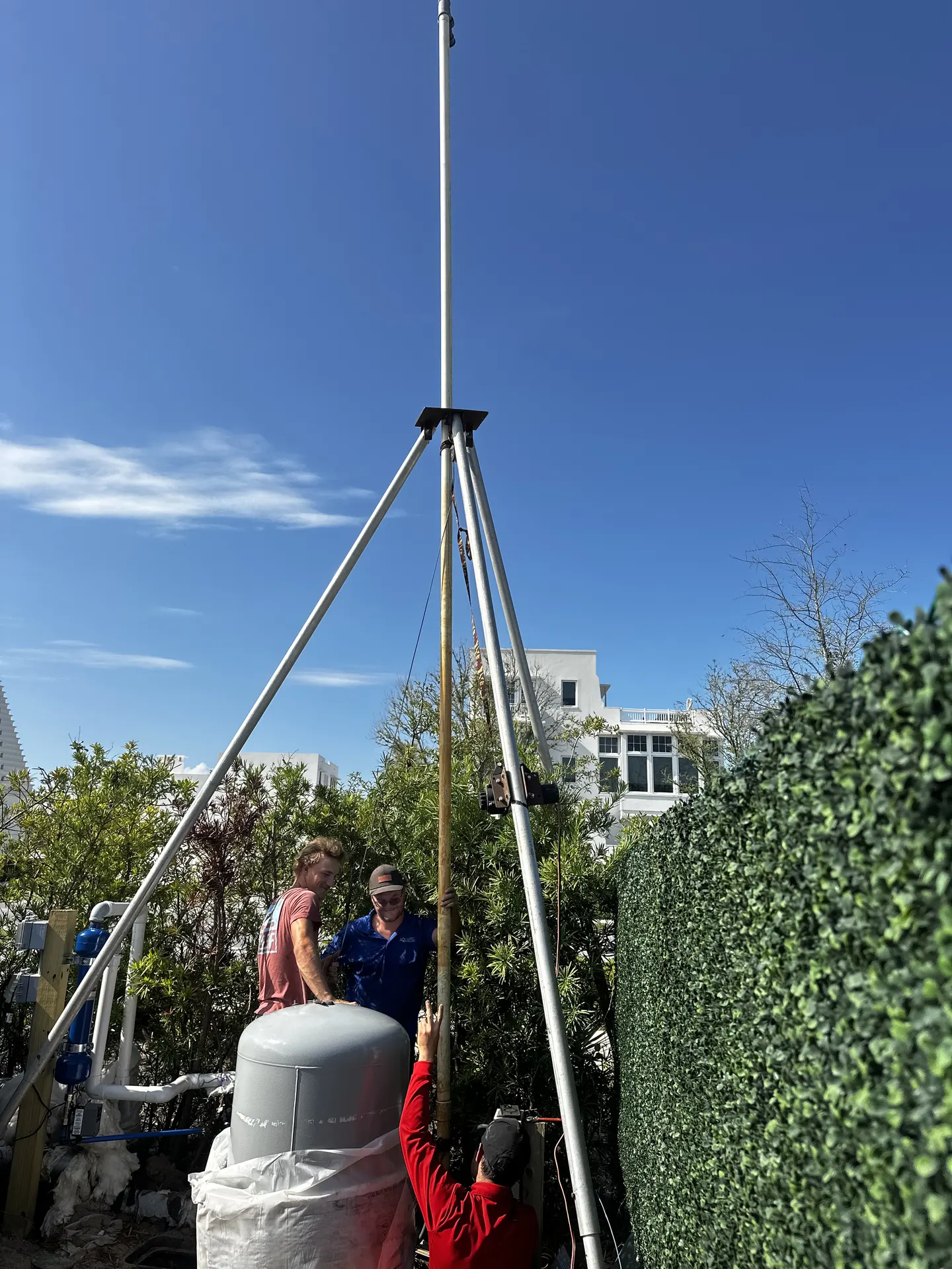 Two crew members on top of a large tank while a third runs the lift