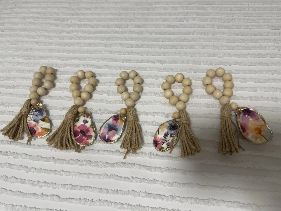 Five natural bead napkin rings with jute tassels and colorful floral oyster shell charms
