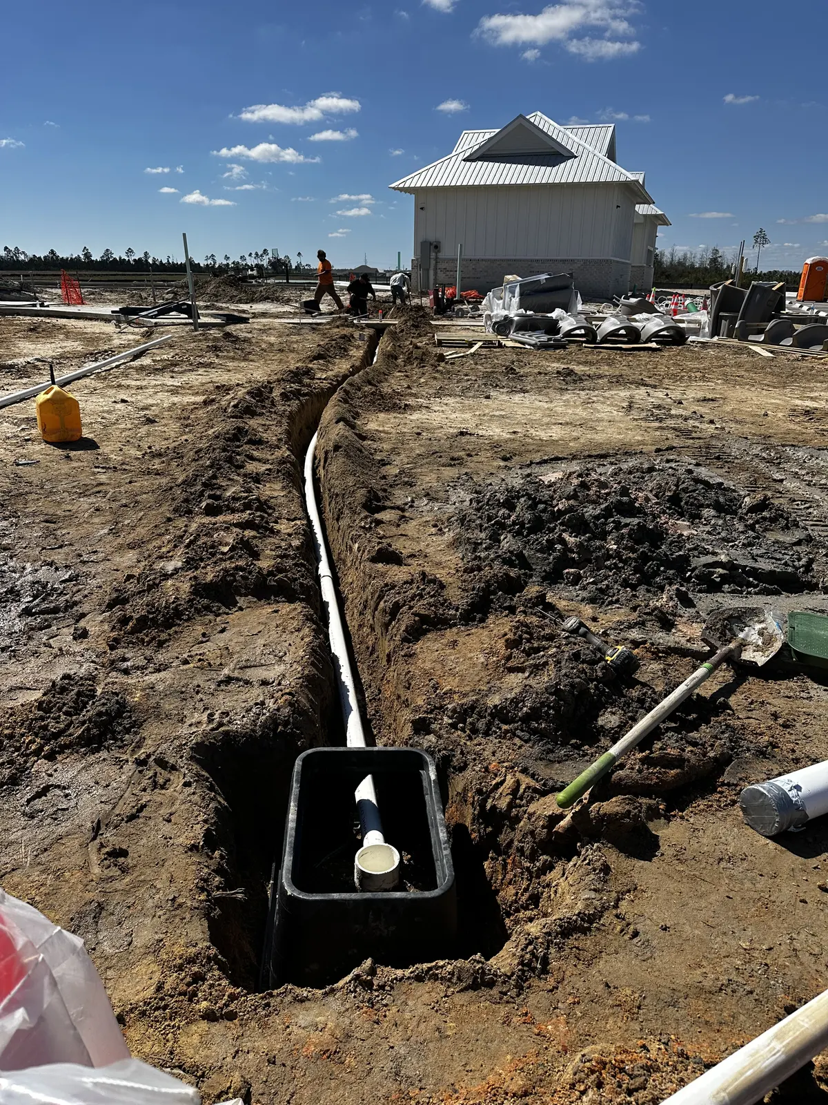 Trench with water line running toward a newly built house