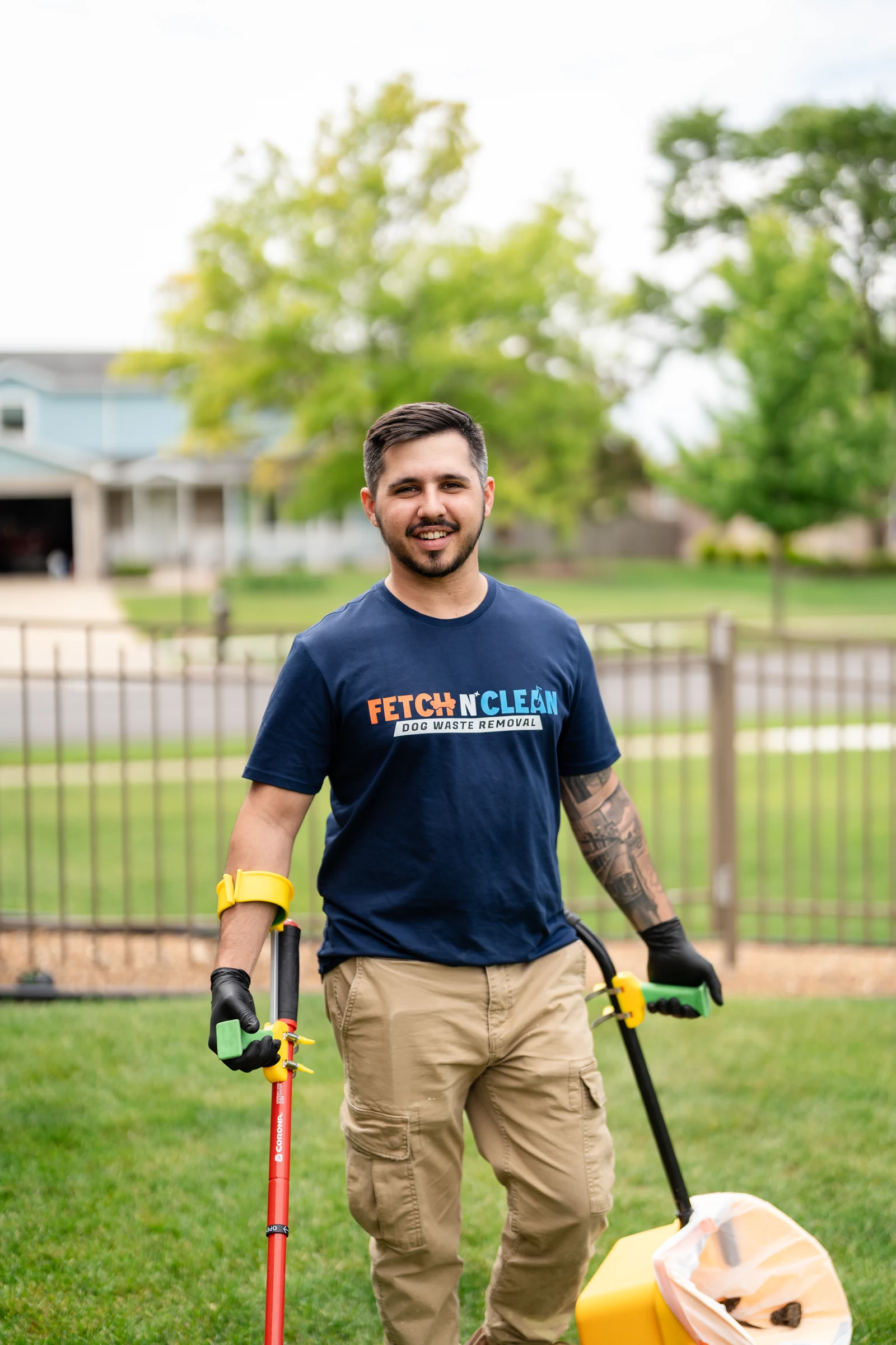 Fetch N Clean team member in gloves holding cleanup tools in a yard.