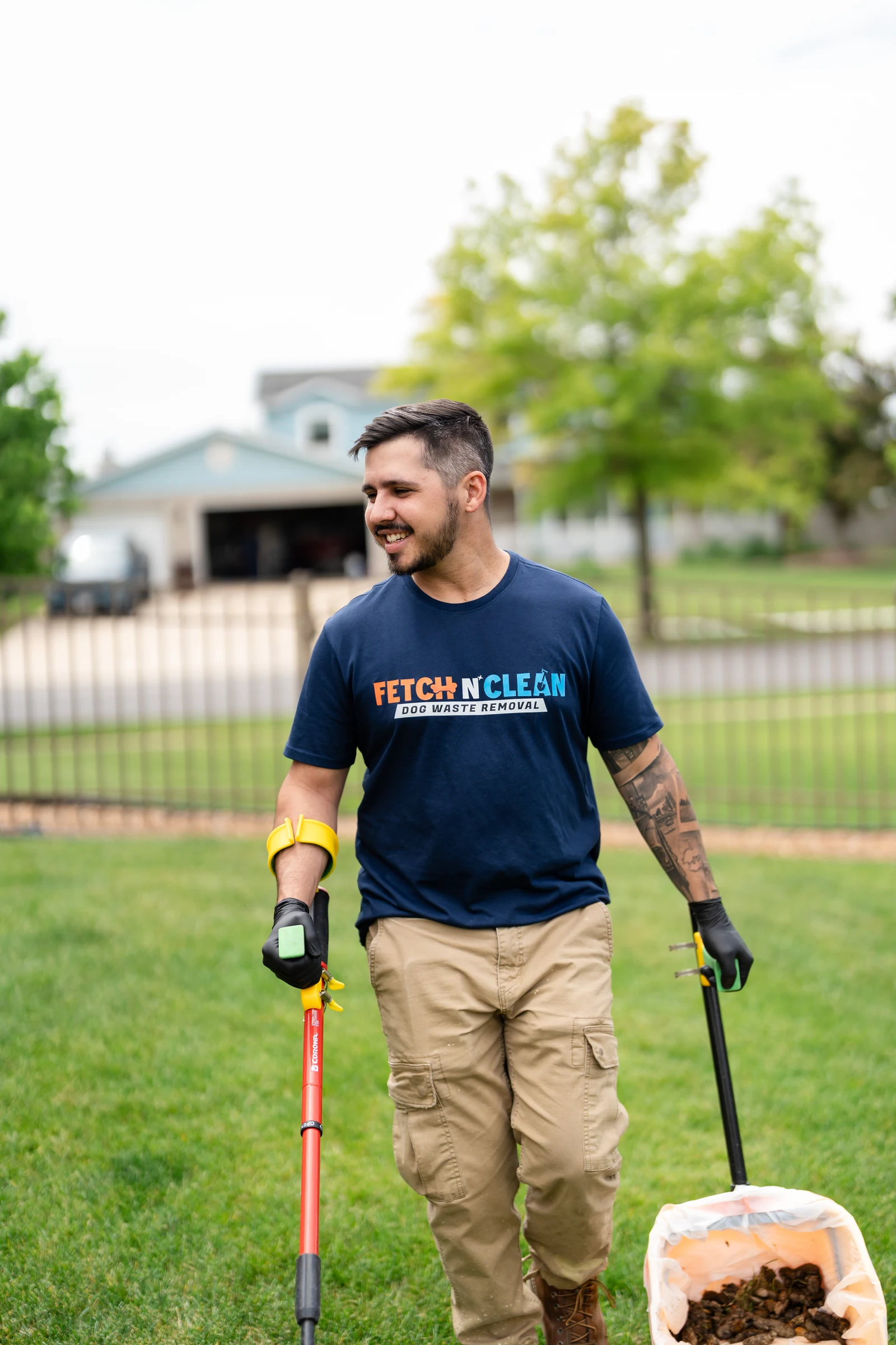 Fetch N Clean team member scooping dog waste with a hand tool in a backyard.