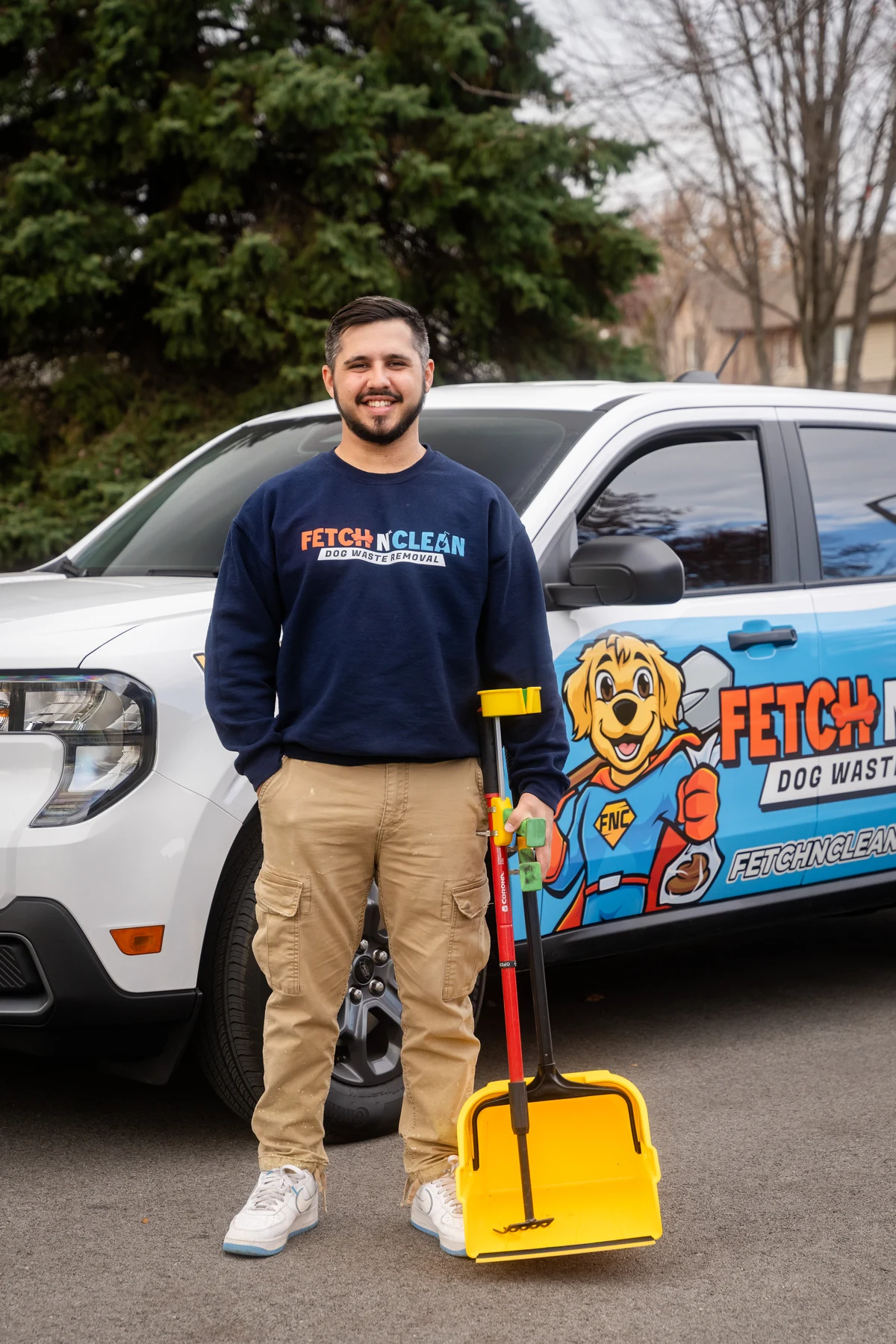 Fetch N Clean team member with a yellow scoop in front of a branded service vehicle.