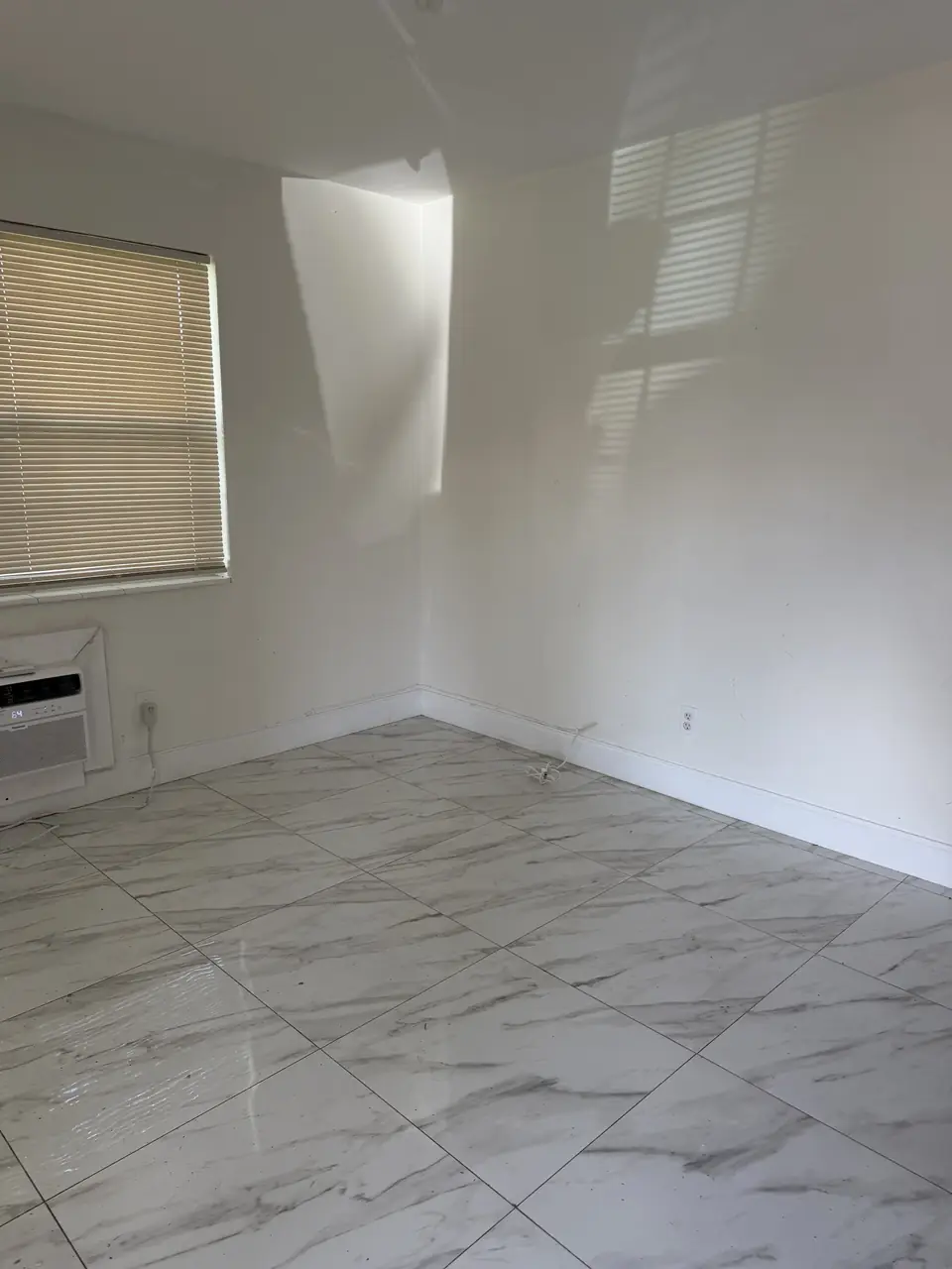 The same living room emptied down to bare tile floors after removal