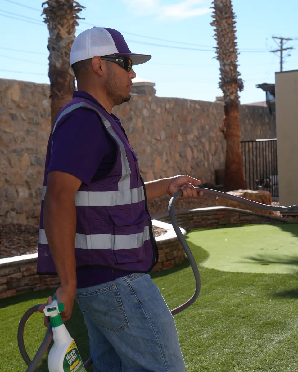 GP Scoops service provider holding a hose on an artificial turf lawn