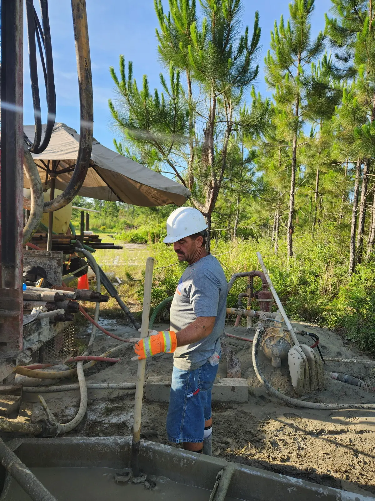 Crew member mixing concrete at a wooded worksite